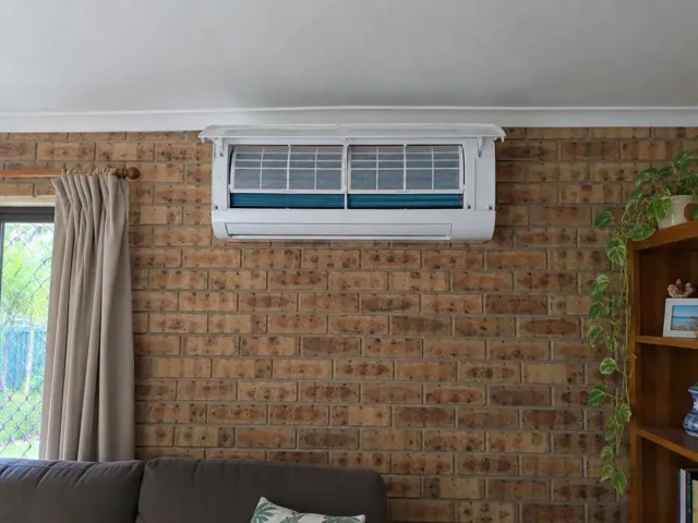 Open split system indoor unit on a brick wall above a lounge in Coombabah